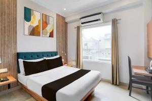 a bedroom with a bed and a desk and a window at Super Townhouse Oak Arvindo Park Indira Nagar Formerly Rama Inn in Vibhuti Khand