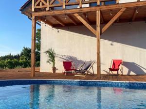two red chairs sitting on a deck next to a swimming pool at Zapach Traw in Ostróda