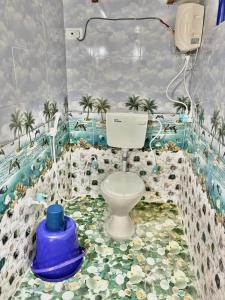 a bathroom with a toilet with palm trees on the floor at Deeksha homestay in Hampi