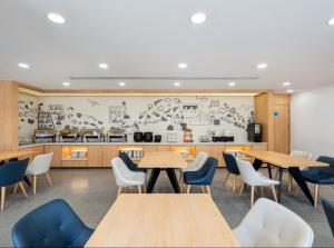 a restaurant with tables and chairs and a kitchen at Hanting Hotel Beijing Wukesong Yongding Road in Beijing