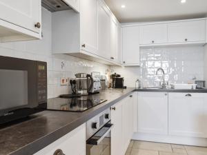 Una cocina blanca con gabinetes blancos y un microondas. en Magdala Garden, en Salcombe