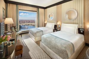 ein Hotelzimmer mit zwei Betten und einem großen Fenster in der Unterkunft Fairmont Nile City in Kairo