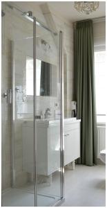W łazience znajduje się szklana kabina prysznicowa i umywalka. w obiekcie Apartamenty Róże i Zen w Toruniu