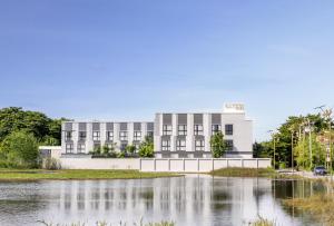 a building in front of a body of water at Gate43 Airport Hotel in Lat Krabang