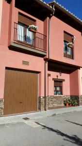 ein rosafarbenes Haus mit Garage und zwei Fenstern in der Unterkunft Casa Rural Claudia in Albarracín