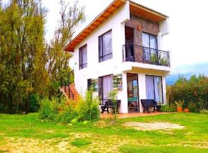 a large white house with a balcony on a lawn at Habitación 201 boutique in Paipa
