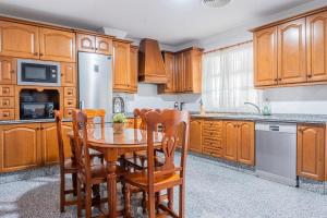 Una cocina con gabinetes de madera y una mesa y sillas. en Villa Candelaria Sevilla Aljarafe, en Bormujos