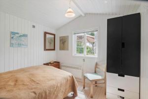 a bedroom with a bed and a chair and a window at 1585-Vejby-Plovmandsvang-27 in Vejby
