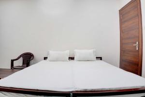 a white bed with two pillows and a chair at Hotel O akshat guest house in Somarda Kauasot