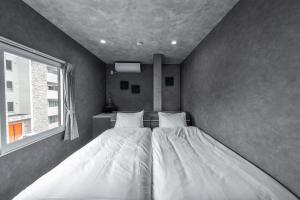two twin beds in a room with a window at The Exstra in Otaru