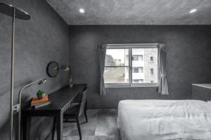a bedroom with a bed and a desk and a window at The Exstra in Otaru