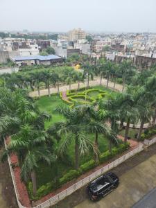 een auto geparkeerd voor een park met palmbomen bij apartment in Jabalpur 