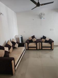 twee banken in een woonkamer met een plafondventilator bij apartment in Jabalpur 