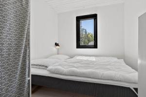 a white bedroom with a bed with a window at 8804-Glesborg-Vesttoften-20 in Glesborg