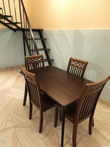 a wooden table with four chairs and a staircase at Econo Homestay in Ipoh