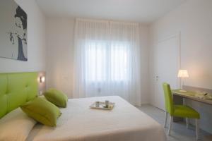 una camera con letto con testiera verde e scrivania di Hotel Solemare - Frontemare - 3 Stelle Superior a Lido di Jesolo