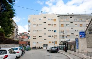 a tall white building with cars parked on a street at Apartment 4 You in Split in Split