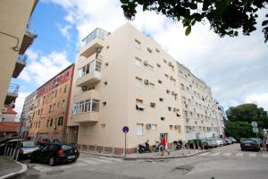 un edificio blanco alto con coches estacionados en un estacionamiento en Apartment 4 You in Split, en Split