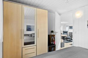 BL856-Blokhus-Soren-Tjenersvej-2 في بلوكهوس: غرفة نوم مع خزانة خشبية كبيرة مع مرآة