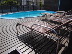 un banc à côté d'une piscine dans l'établissement Apartamento Em Andar Alto com Vista Mar Meireles, à Fortaleza