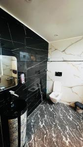 een badkamer met een wit toilet en een zwarte muur bij The Scenic Roofhouse by Amrove near Rajpur road in Dehradun +38 foto's