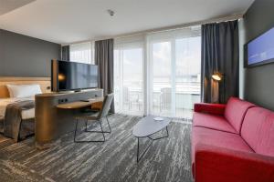 a hotel room with a couch and a tv at Best Western Plus Hotel Papenburg in Papenburg