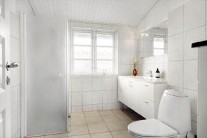un bagno bianco con un water e un lavandino di BL1284-Blokhus-Tyttebaervej-4 a Blokhus Altre 29 foto