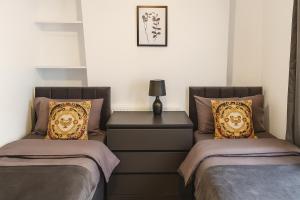 a bedroom with two beds and a night stand with a lamp at Stunning 5 Bedroom Home in the Heart of Swansea - Snooker Table, WiFi & Parking! in Swansea