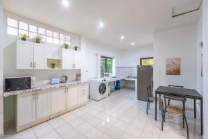cocina con armarios blancos, mesa y fogones en Serenity Holiday Villa 1 D Karon Beach, en Karon Beach