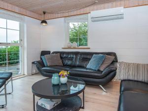 a living room with a leather couch and a table at 4 star holiday home in Allingåbro in Nørager +37 photos