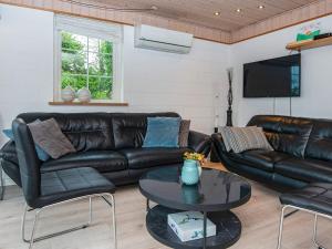 a living room with a leather couch and a table at 4 star holiday home in Allingåbro in Nørager