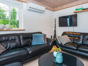 a living room with a leather couch and a table at 4 star holiday home in Allingåbro in Nørager