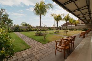 Un patio con mesas y sillas y palmeras. en Kubu Wana Villa, en Uluwatu