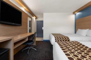 a hotel room with two beds and a desk and a tv at Travelodge by Wyndham Blairmore in Blairmore