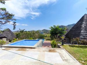 a villa with a swimming pool and thatched roofs at Golo Pada Villa Labuan Bajo by ABM in Nggorang