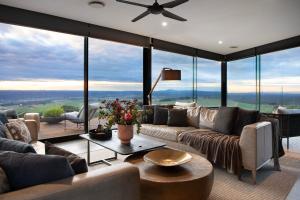 a living room with couches and a ceiling fan at Sky High- iconic ridge-top retreat in Hepburn Springs