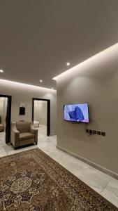 a living room with a couch and a tv on a wall at شقة فندقية بمجمع هوازن السكني in Ash Sharāʼi‘