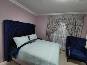 a bedroom with a bed and a blue chair at Blackpony Guesthouse in Kriel