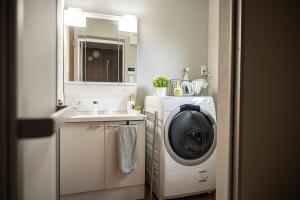 a laundry room with a washing machine and a sink at The Emu Park Tsushima in Tsushima