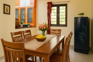a dining room with a table and a refrigerator at Skandanam Ecoville Homestay Tirupati - City Center Premium Garden Villa Stay Center of City With Ultra Modern Facilities, Kitchen, 24 Hours Care Taker, Maid, Wifi, Private Rooms, Full Amenities in Tirupati