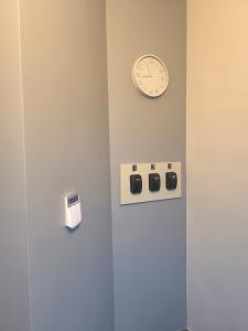 a clock on a wall next to a wall with switches at Apartamentai1 in Utena