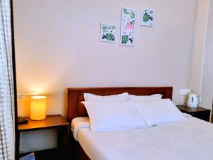 a bedroom with a bed with white sheets and two tables at Breeze Vale Homestay in Shillong