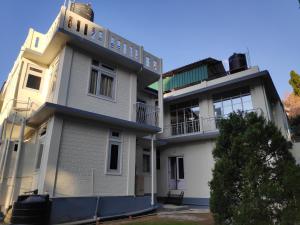 a white building with a balcony on top of it at Breeze Vale Homestay in Shillong +6 photos