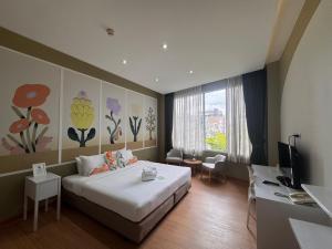 a bedroom with a bed and a desk and a television at Beat Hotel Bangkok in Bangkok
