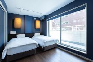 a bedroom with two beds and a large window at yah homes takasago in Fukuoka