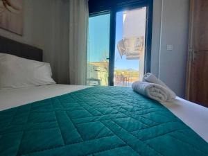 a bedroom with a bed with a green blanket and a window at Chloe Stay Complex by Horizon Homes in Orfánion