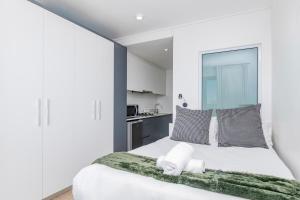 Un dormitorio con una cama blanca con una manta verde. en Stylish Studio in One on Albert, en Hout Bay 11 fotos más