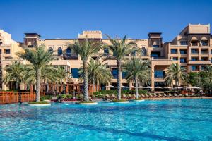 une grande piscine avec des palmiers en face d'un bâtiment dans l'établissement Saadiyat Rotana Resort and Villas, à Abu Dhabi