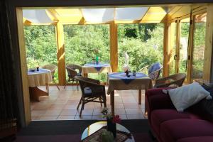 a conservatory with tables and chairs on a patio at Frauenpension Arleta - Women only in Goslar