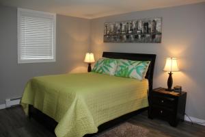 a bedroom with a bed with a green bedspread and two lamps at Serendib Bed and Breakfast in Stratford